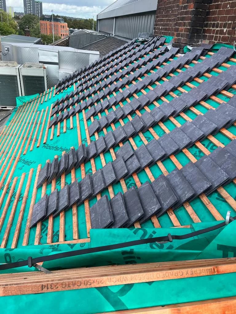 New Welsh slate being laid over fresh felt and treated battens on the Leeds Grand Theatre slope during the heritage refurbishment.