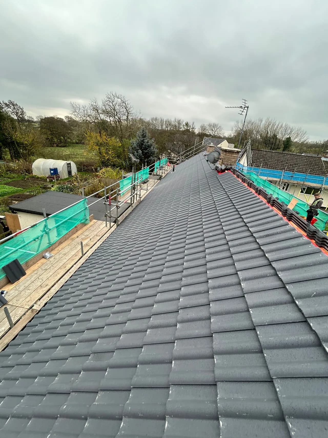 Completed social housing roof replacement with new grey tiled coverings against the County Durham countryside.