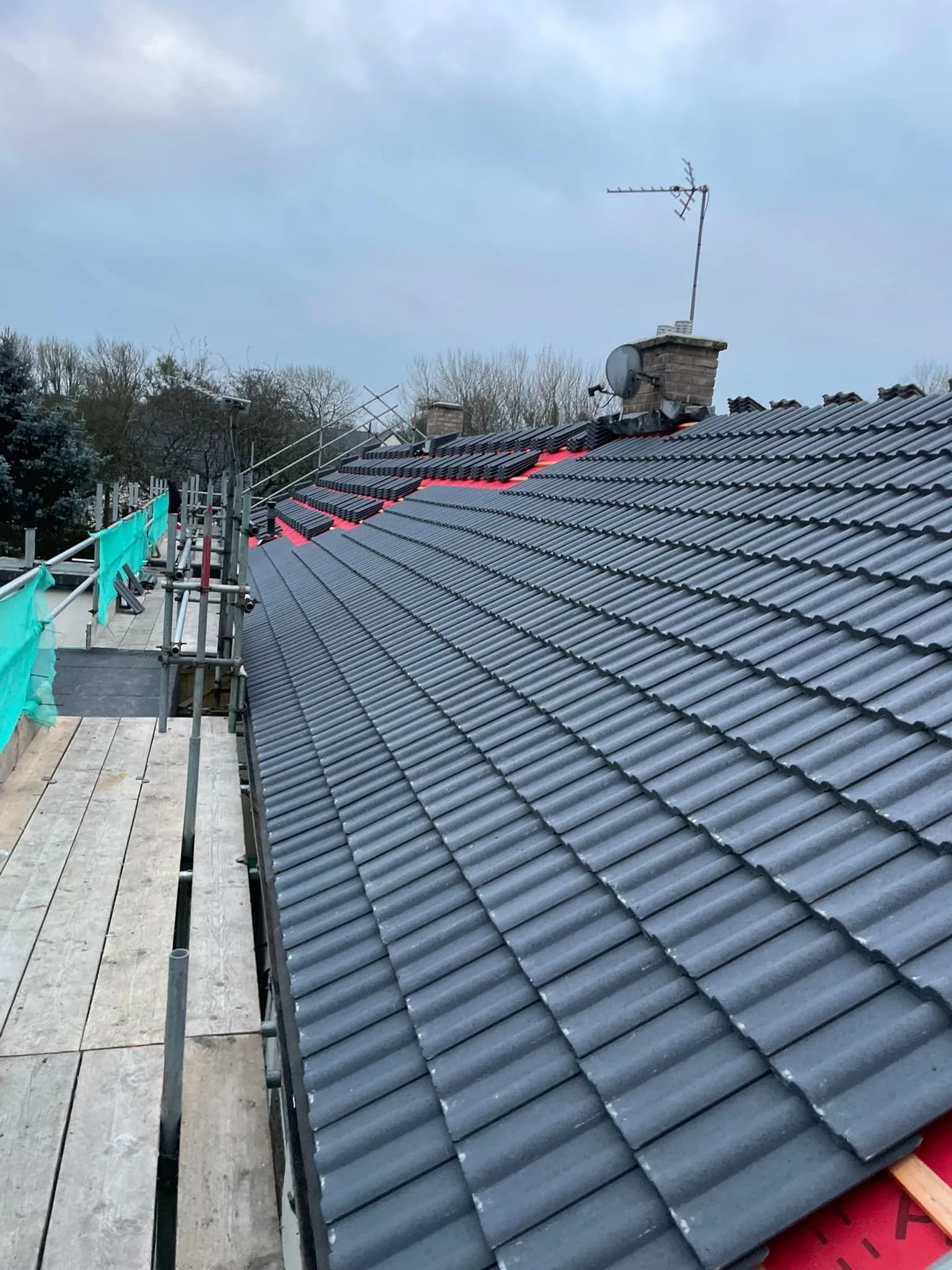 Completed social housing roof replacement at The Close, Cotherstone, with new grey tiled coverings and ridge against the County Durham sky.